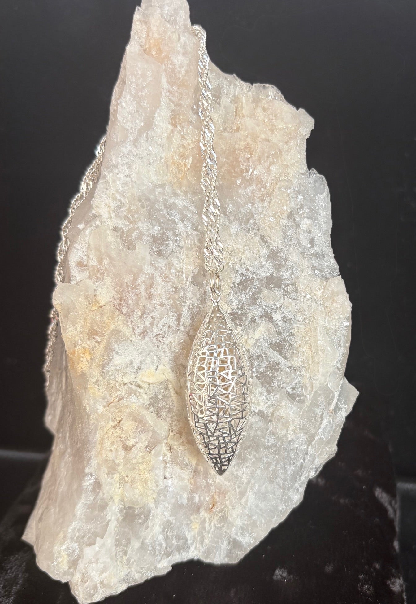 Silver necklace with a pendant on a rock-like surface