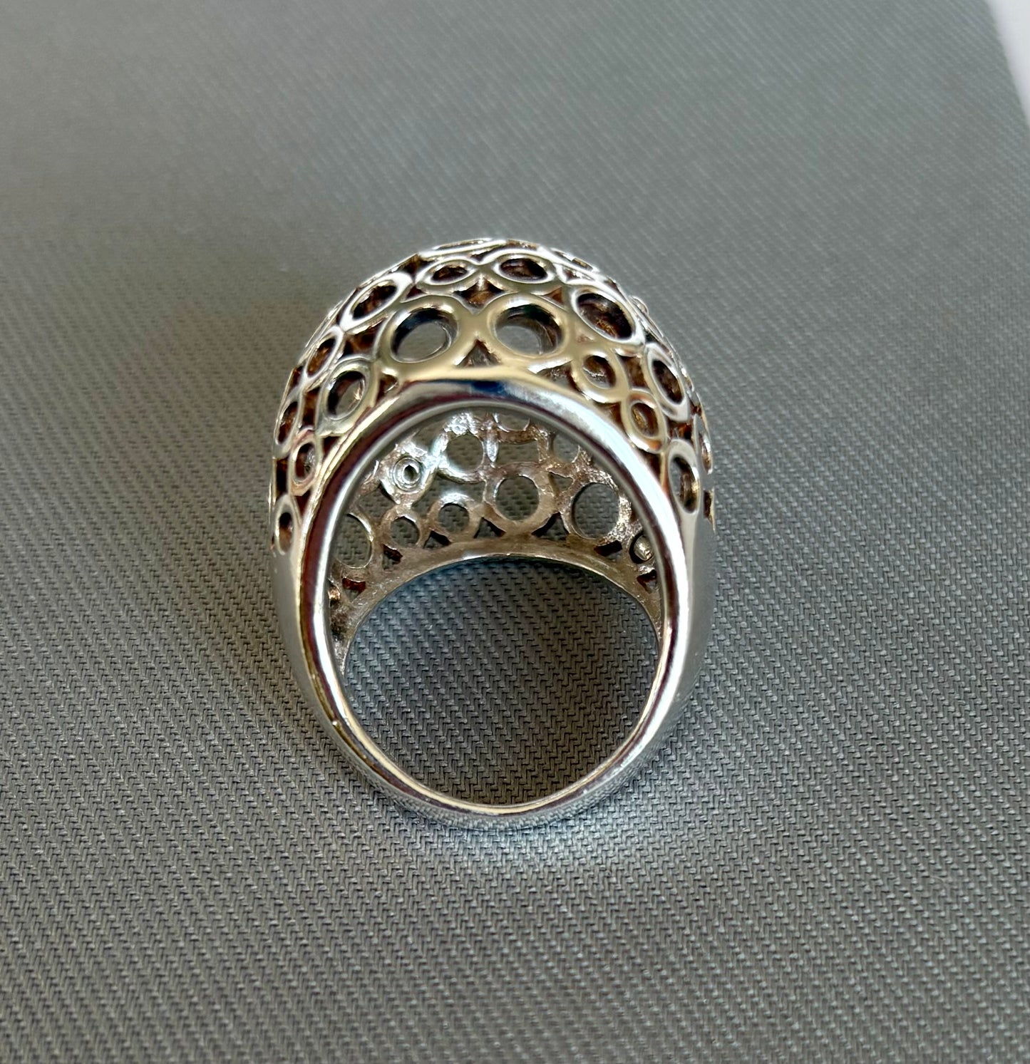 Silver ring with intricate design on a gray surface