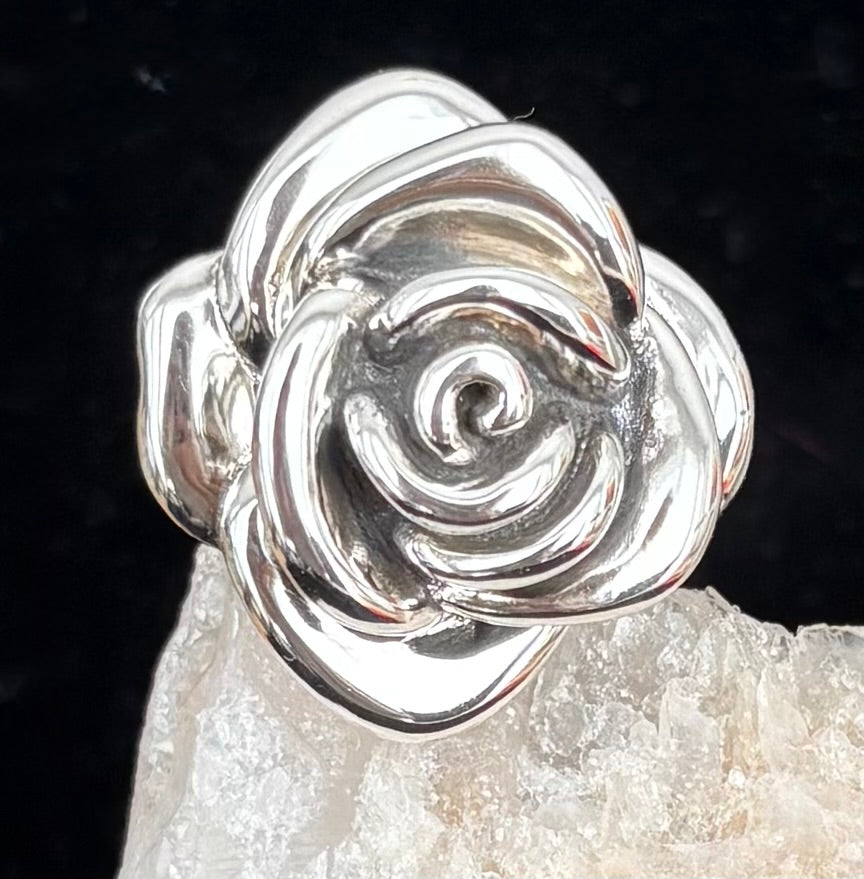 Silver rose-shaped ring on a dark background