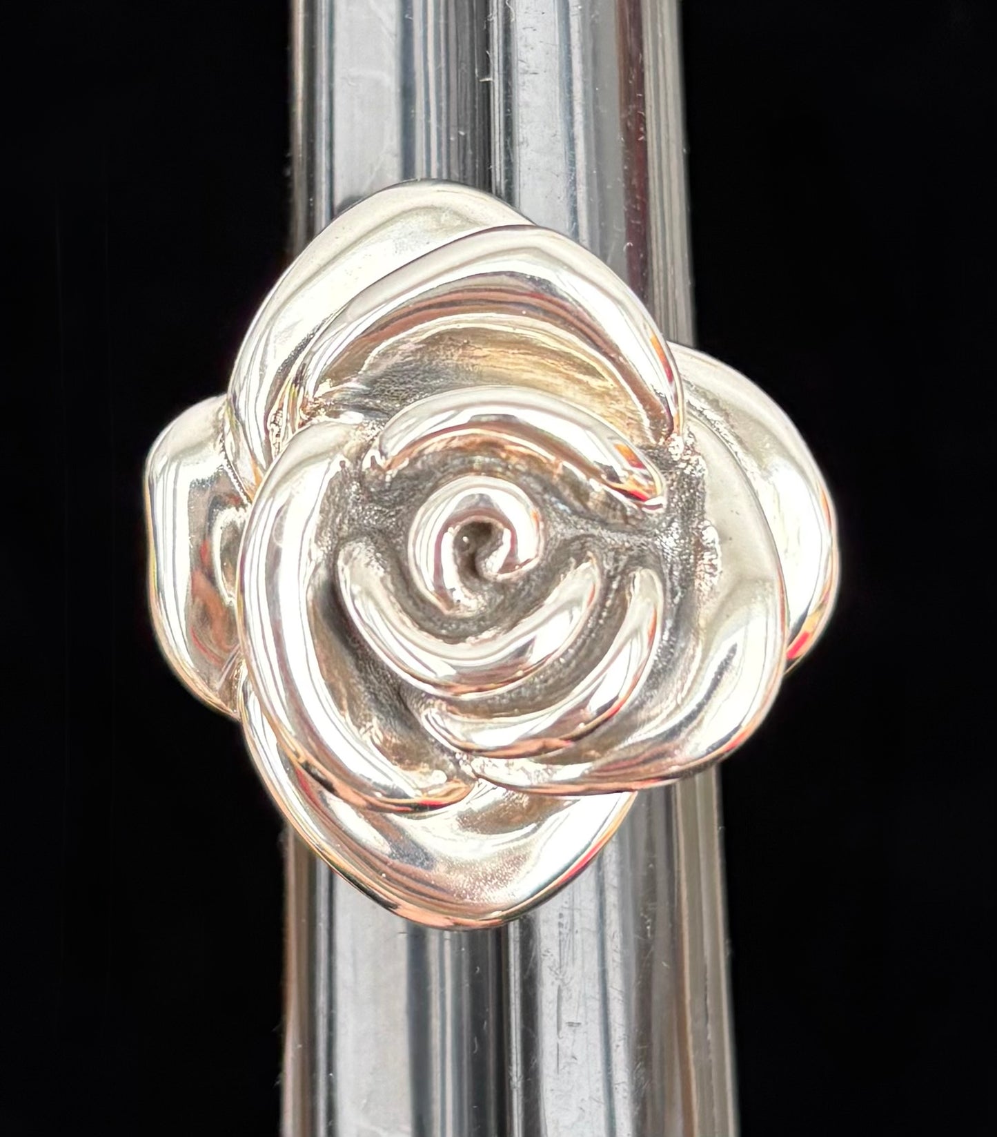 Silver rose-shaped ring on a black background