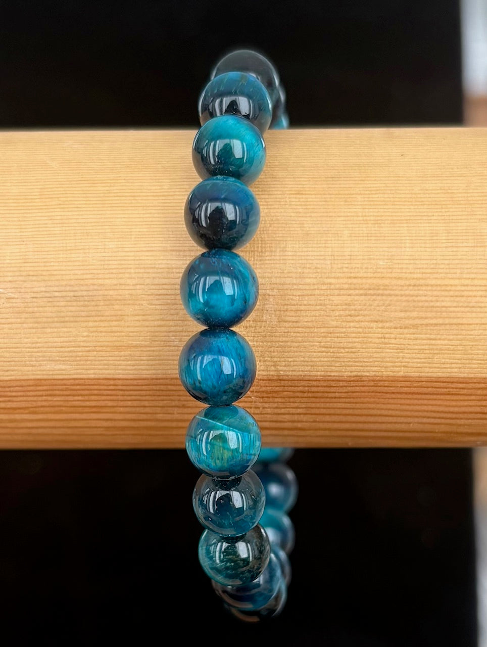 Blue gemstone beaded bracelet on a wooden surface with a black background