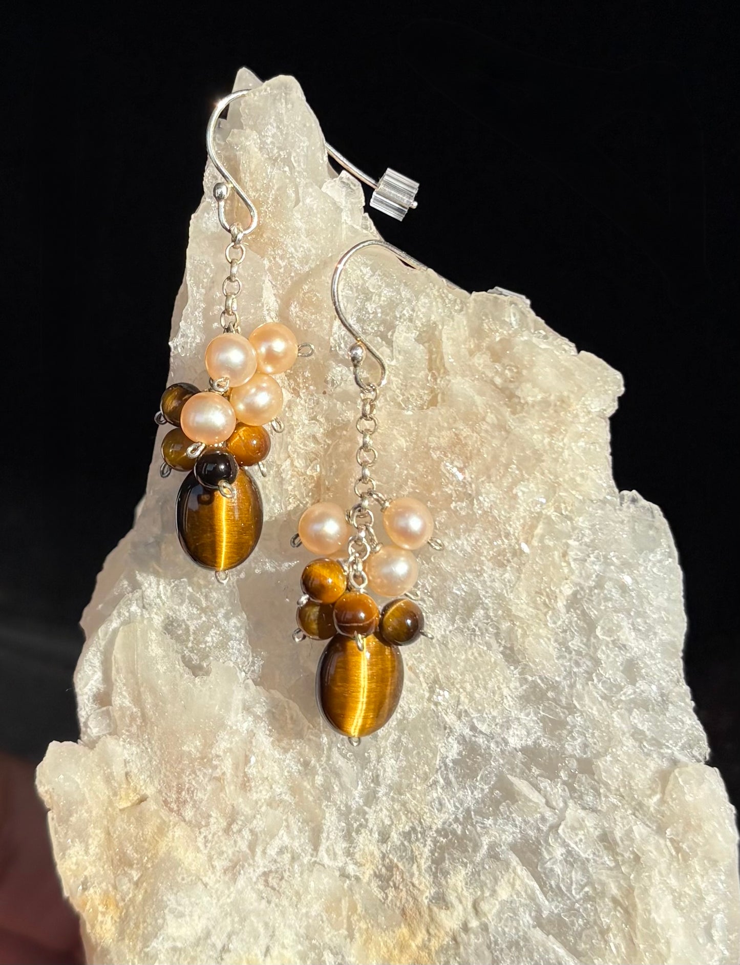 Pair of earrings with tiger eye stones and pearls on a crystal rock