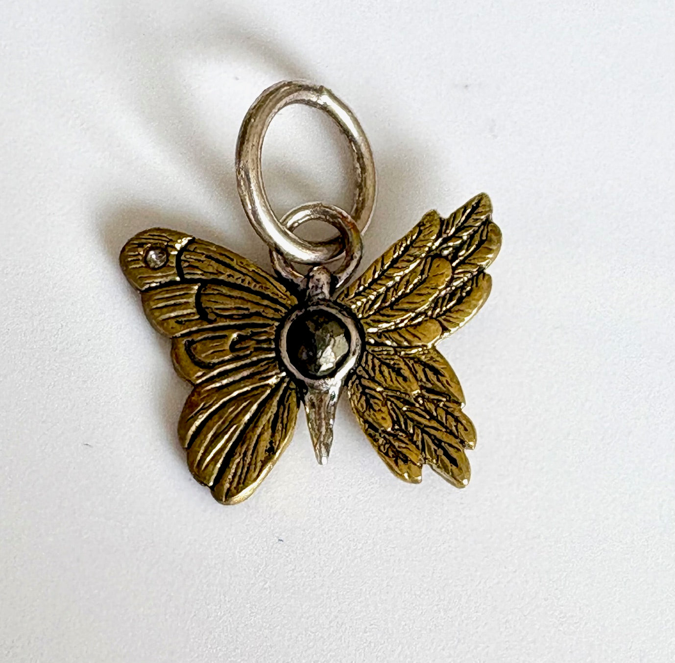 Butterfly-shaped charm with gold and silver finish on a white background