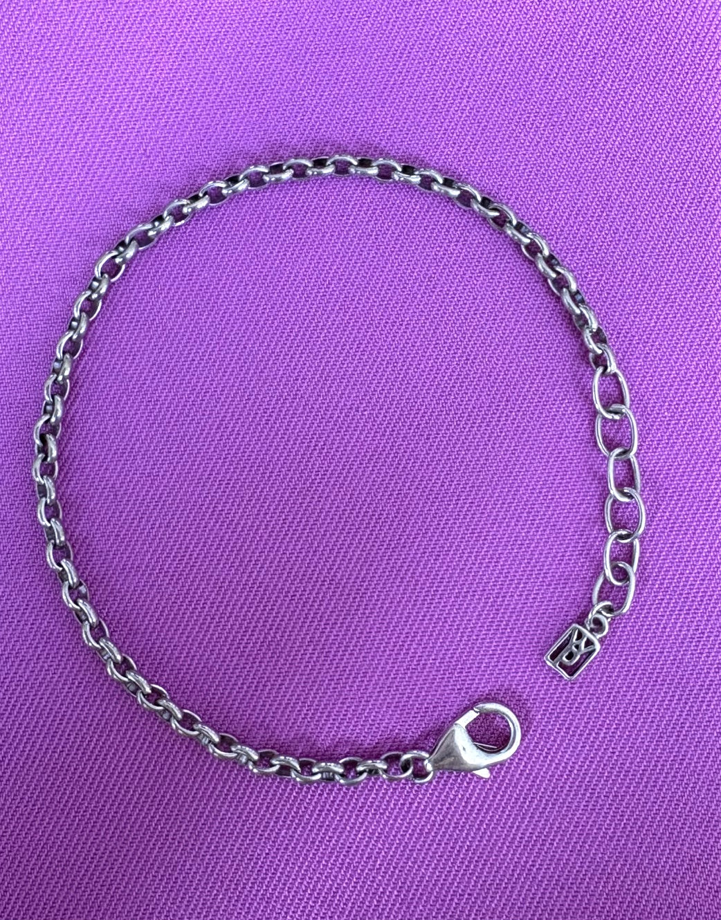 Waxing Poetic sterling silver chain bracelet on a purple background