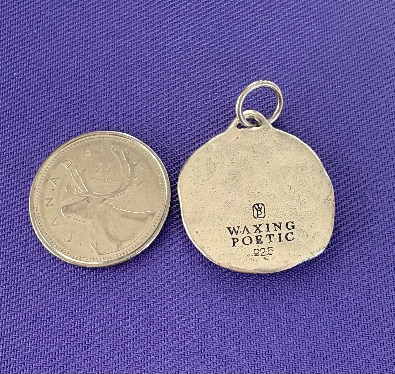 Silver pendant with 'Waxing Poetic' engraving on a purple background
