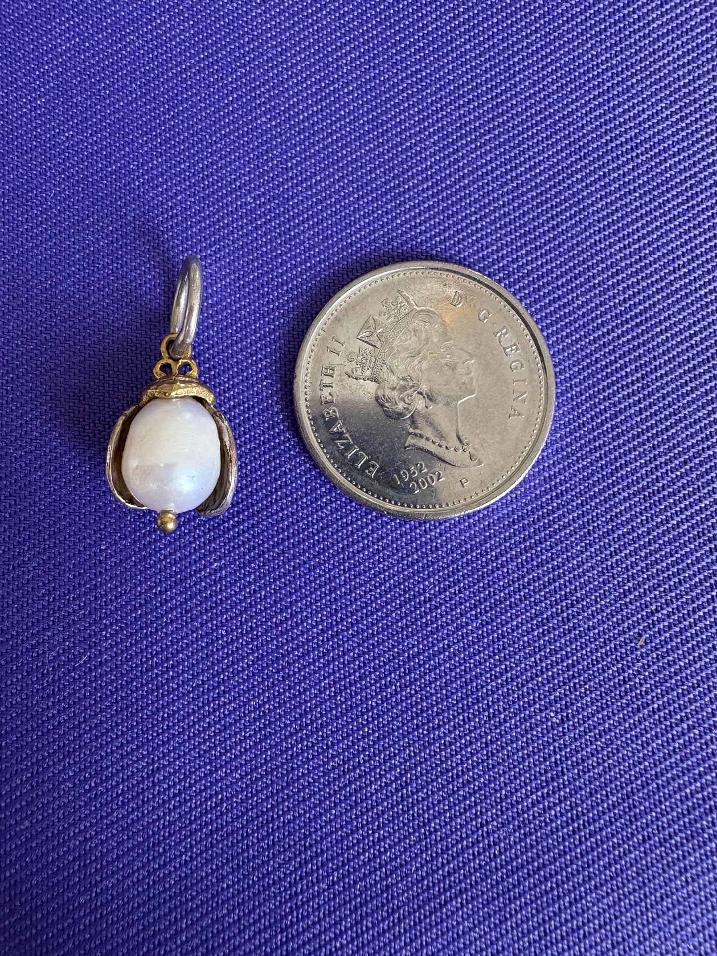 Small pendant with a white pearl on a blue fabric background