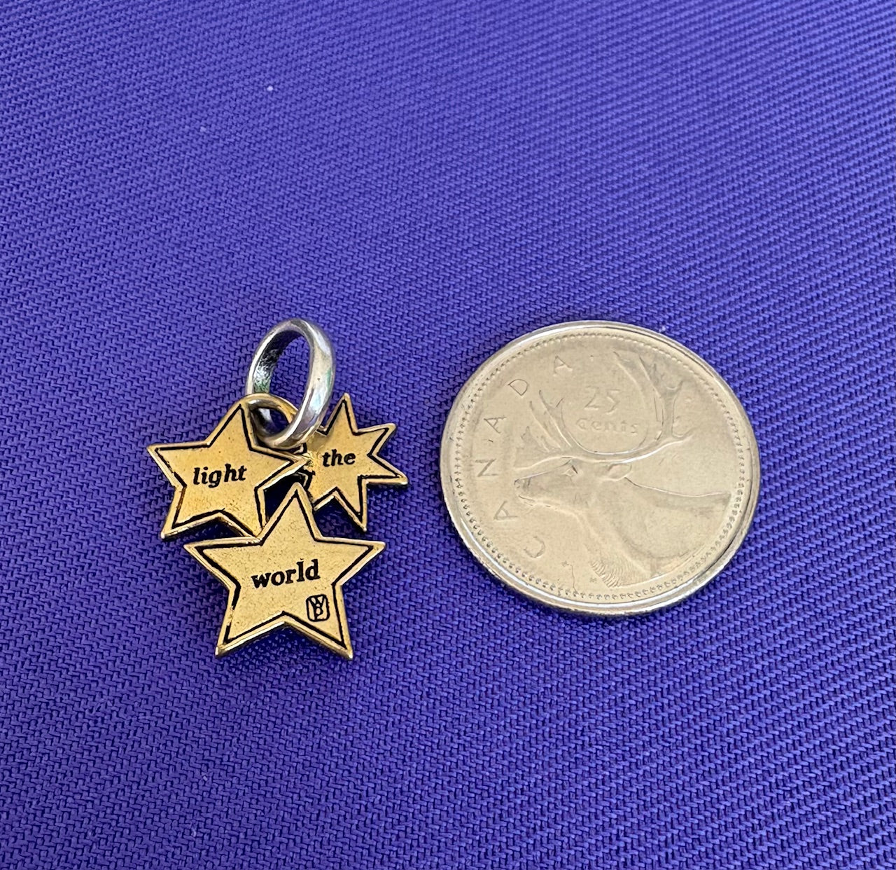 Gold star-shaped pendant with 'light the world' text on a blue background