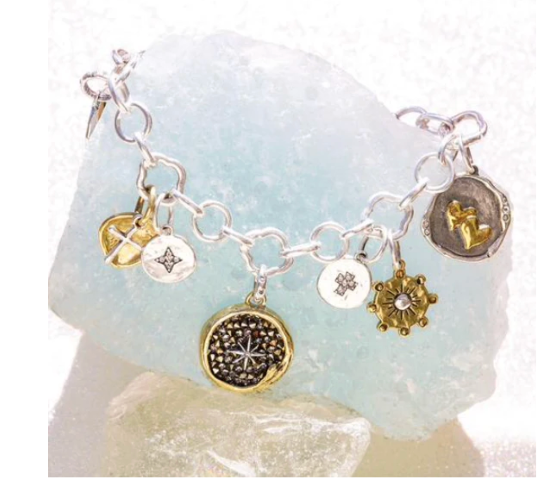 Silver bracelet with various charms on a light blue stone background