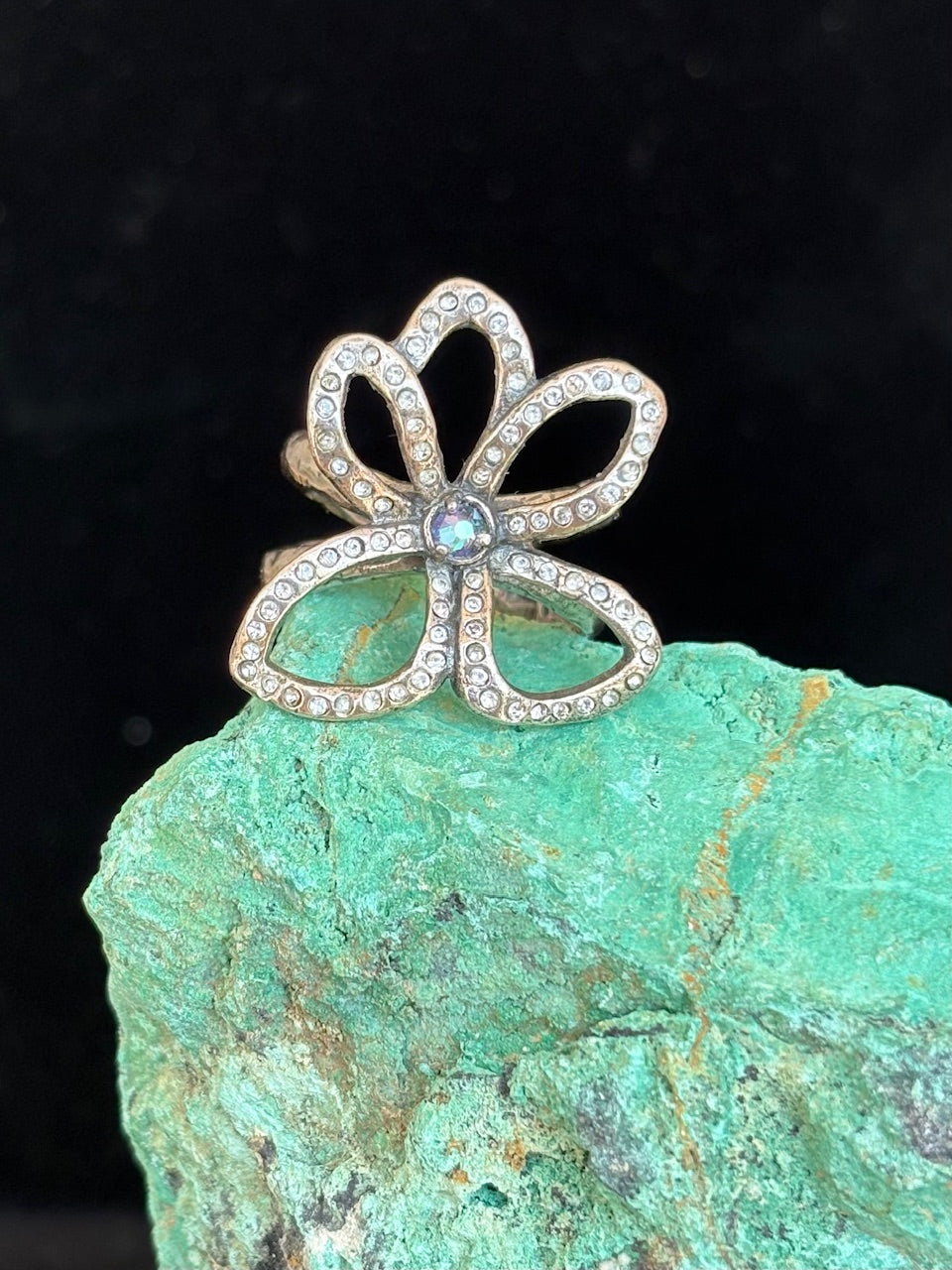Silver flower ring with gemstones on a green stone