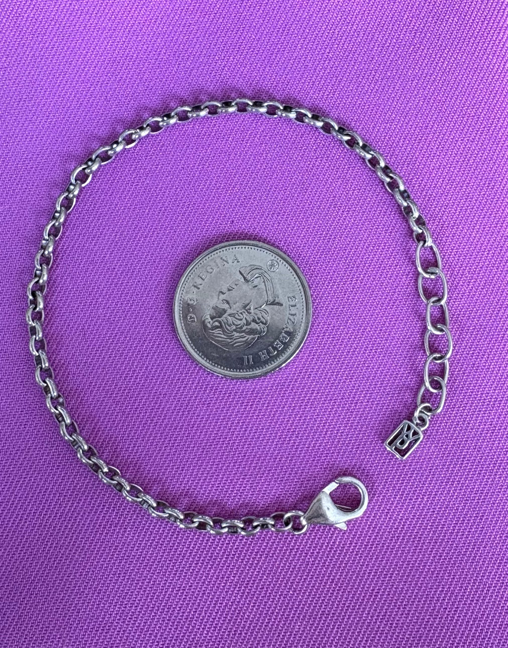Silver chain bracelet with clasp on a purple background