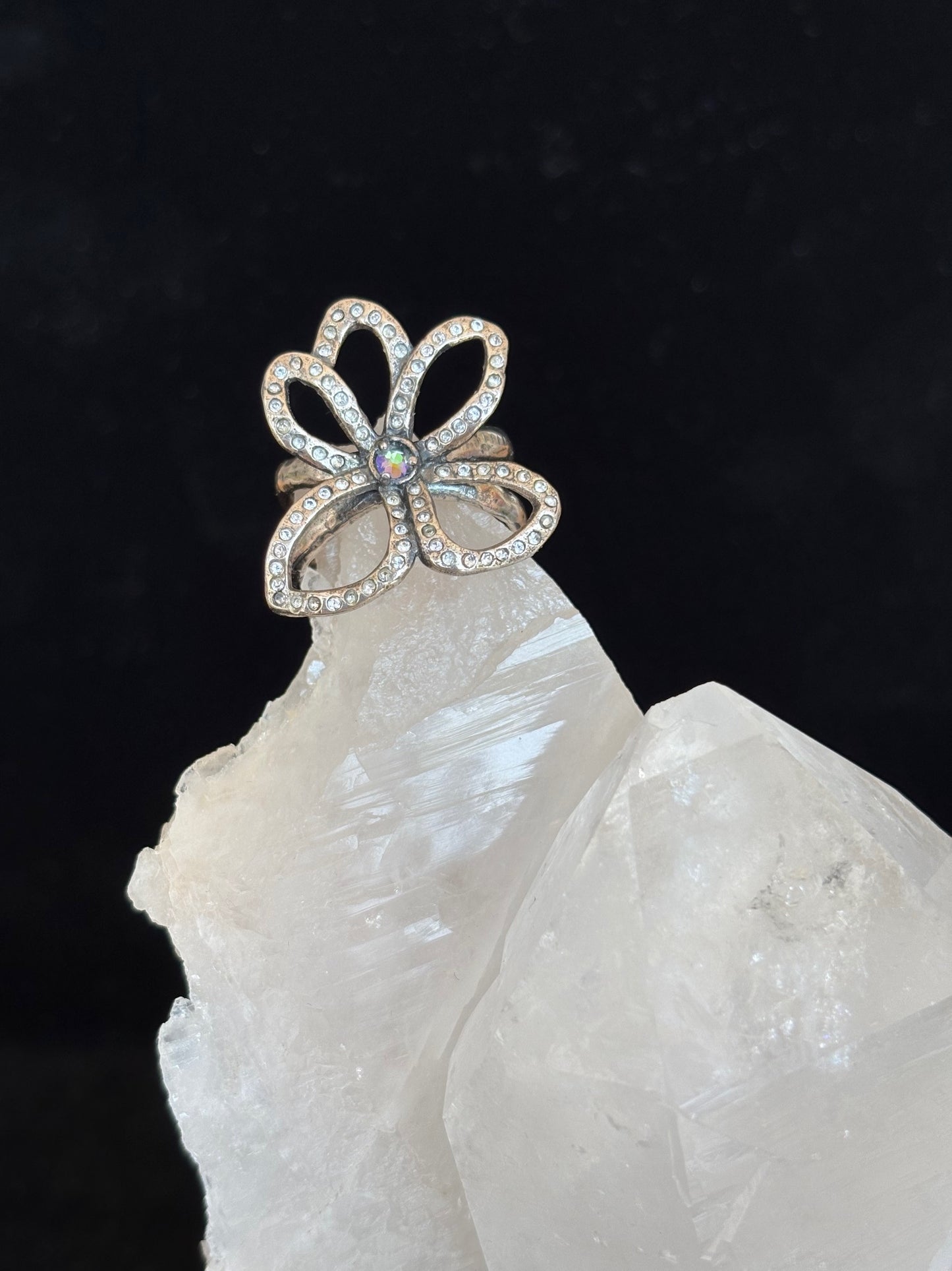 Flower-shaped silver ring with swarovski crystals on a dark background