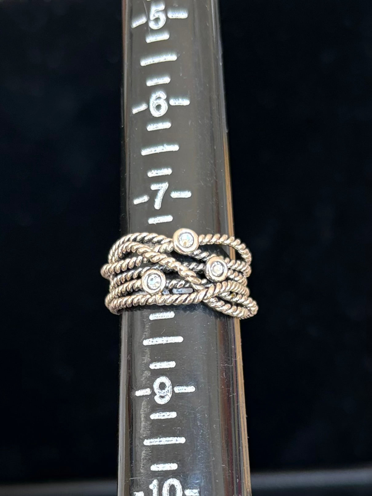Sterling silver ring with swarovski crystal accents on a ruler for size reference against a black background