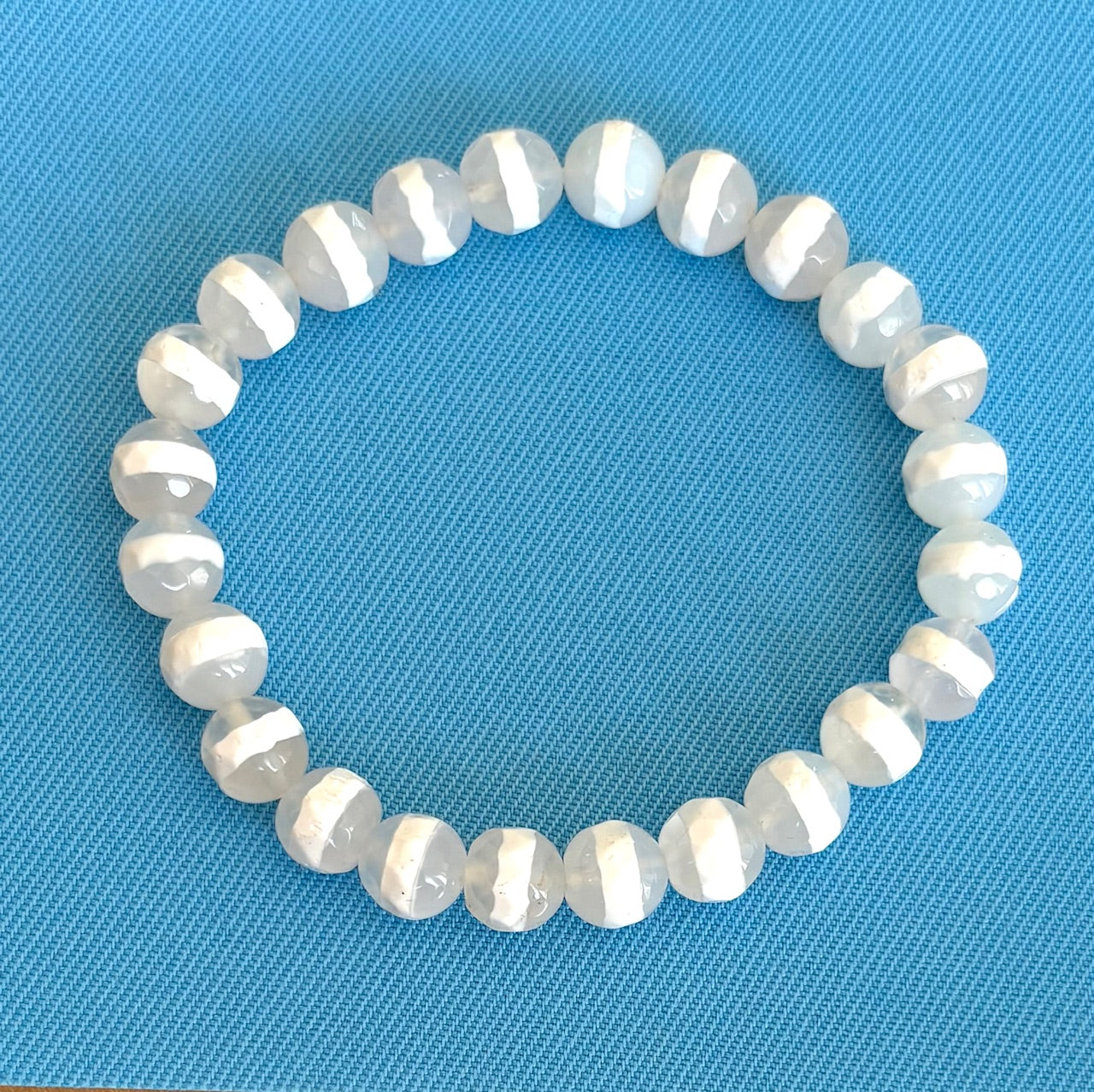 White gemstone bracelet on a blue textured background