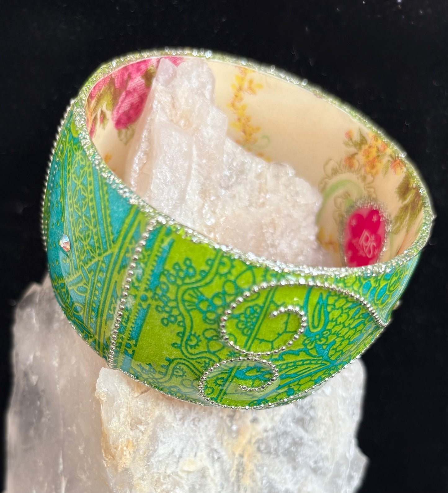 Decorative green bangle on a white crystal with a black background