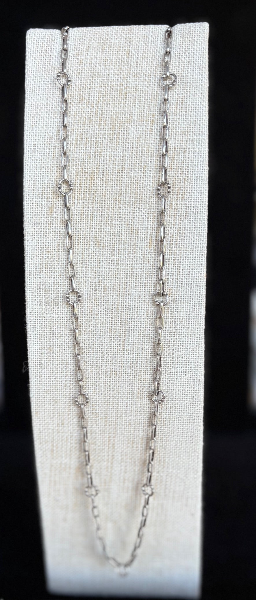 Silver chain necklace on a white card with a black background