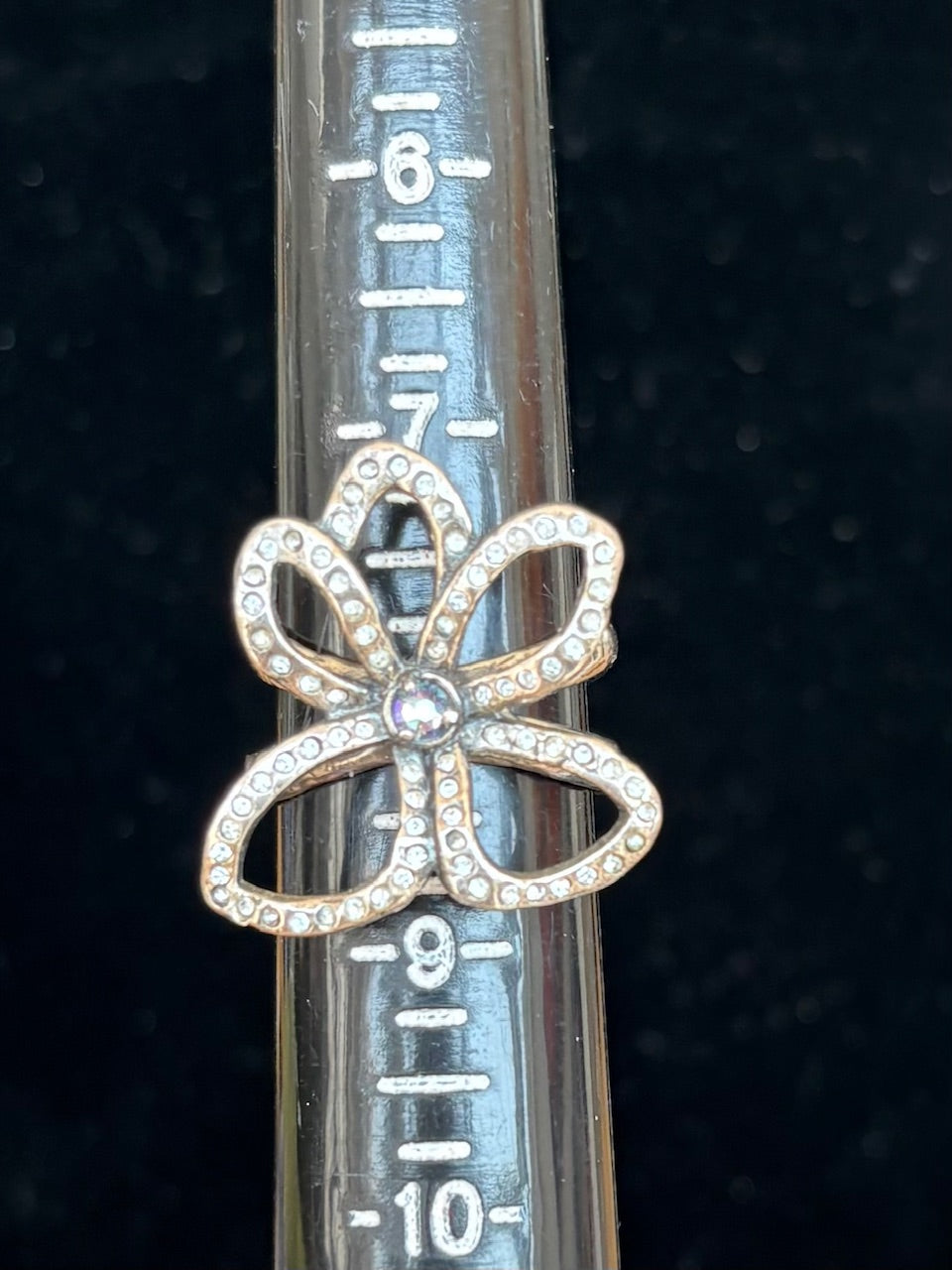 Stelring silver flower shaped ring with clear crystals on a ruler for scale