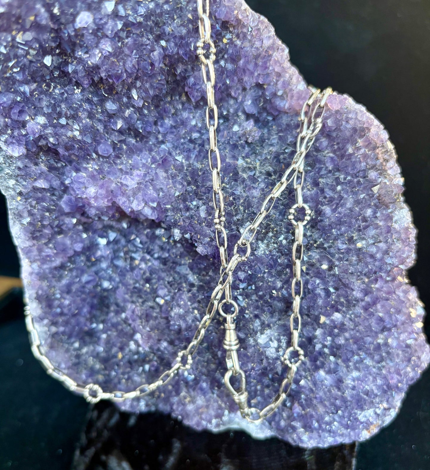 Silver chain necklace on a purple crystal background