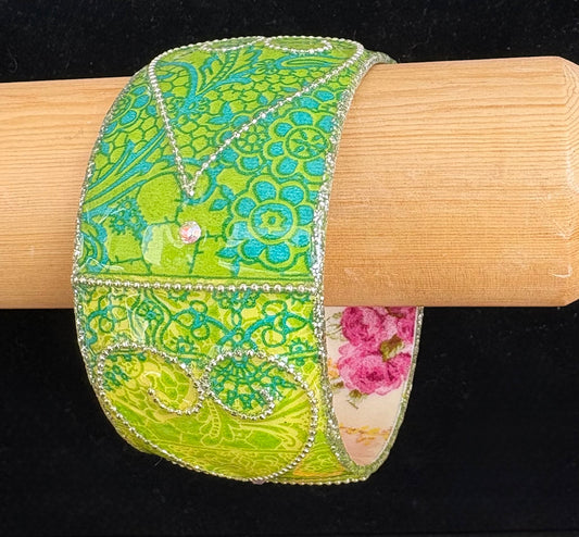 Green floral bracelet on a wooden display stand against a black background