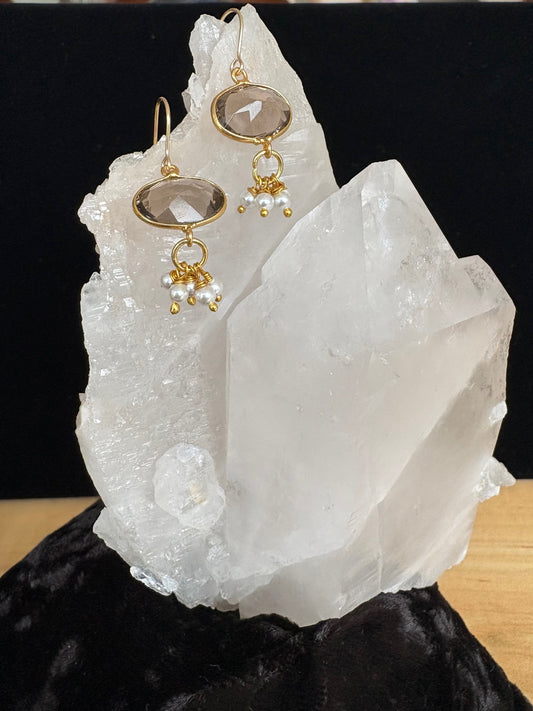 Jolie Esprit Gold earrings with smoky quartz and pearls on a white stone surface