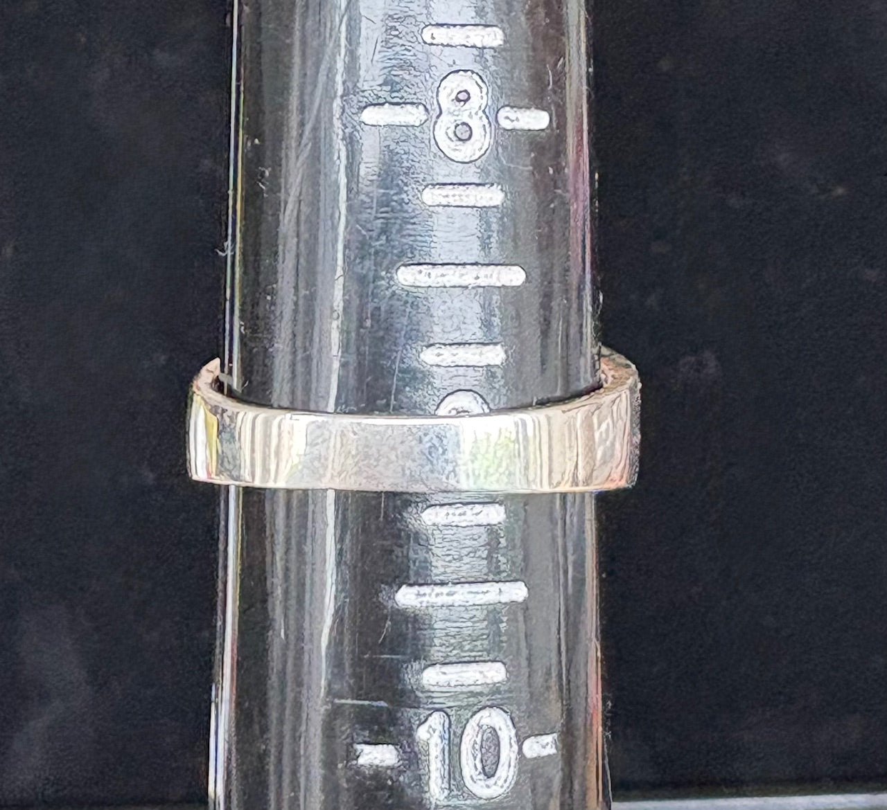 Silver ring  on a cylindrical metal object with measurement markings.