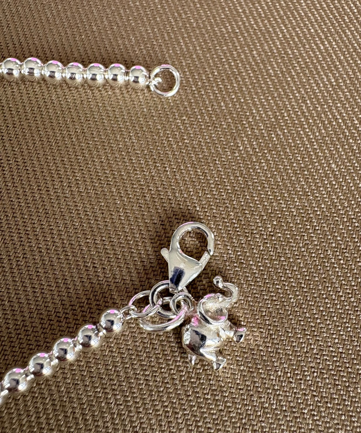 Silver bracelet with a small charm on a brown textured background