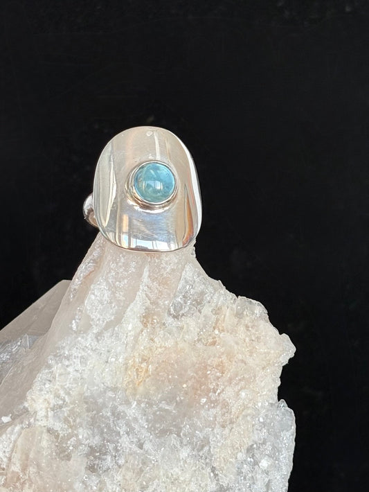 Sterling silver ring with a blue topaz stone on a crystal base against a black background