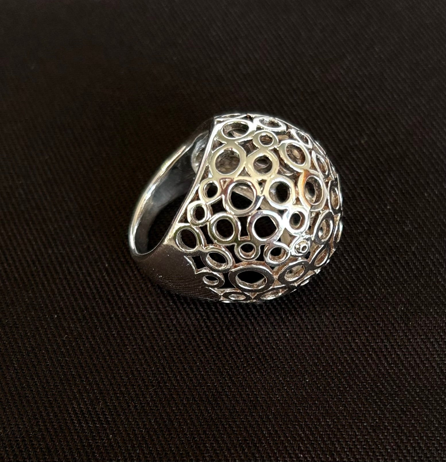 Silver ring with intricate design on a black background