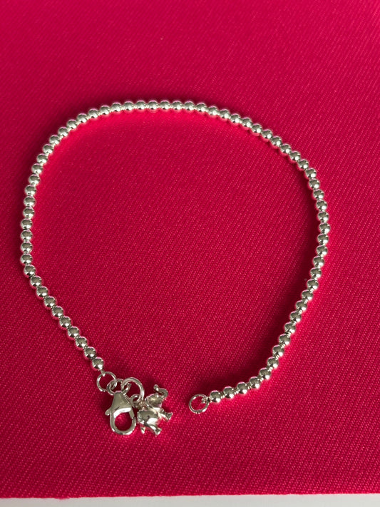 Jolie Esprit sterling silver bracelet with a small charm on a red background