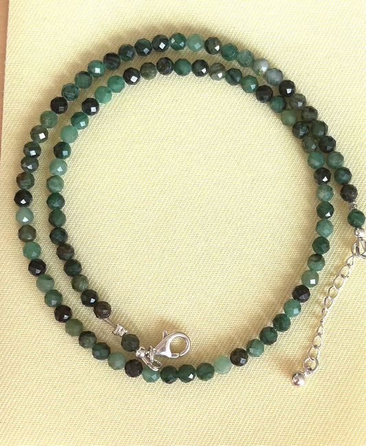 Faceted Emerald necklace on a beige background