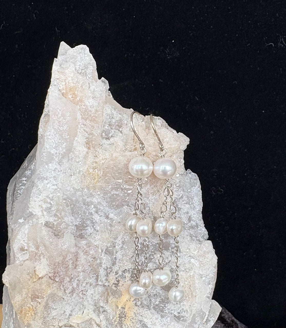 Jolie Esprit pearl dangle earrings on a crystal rock with a black background
