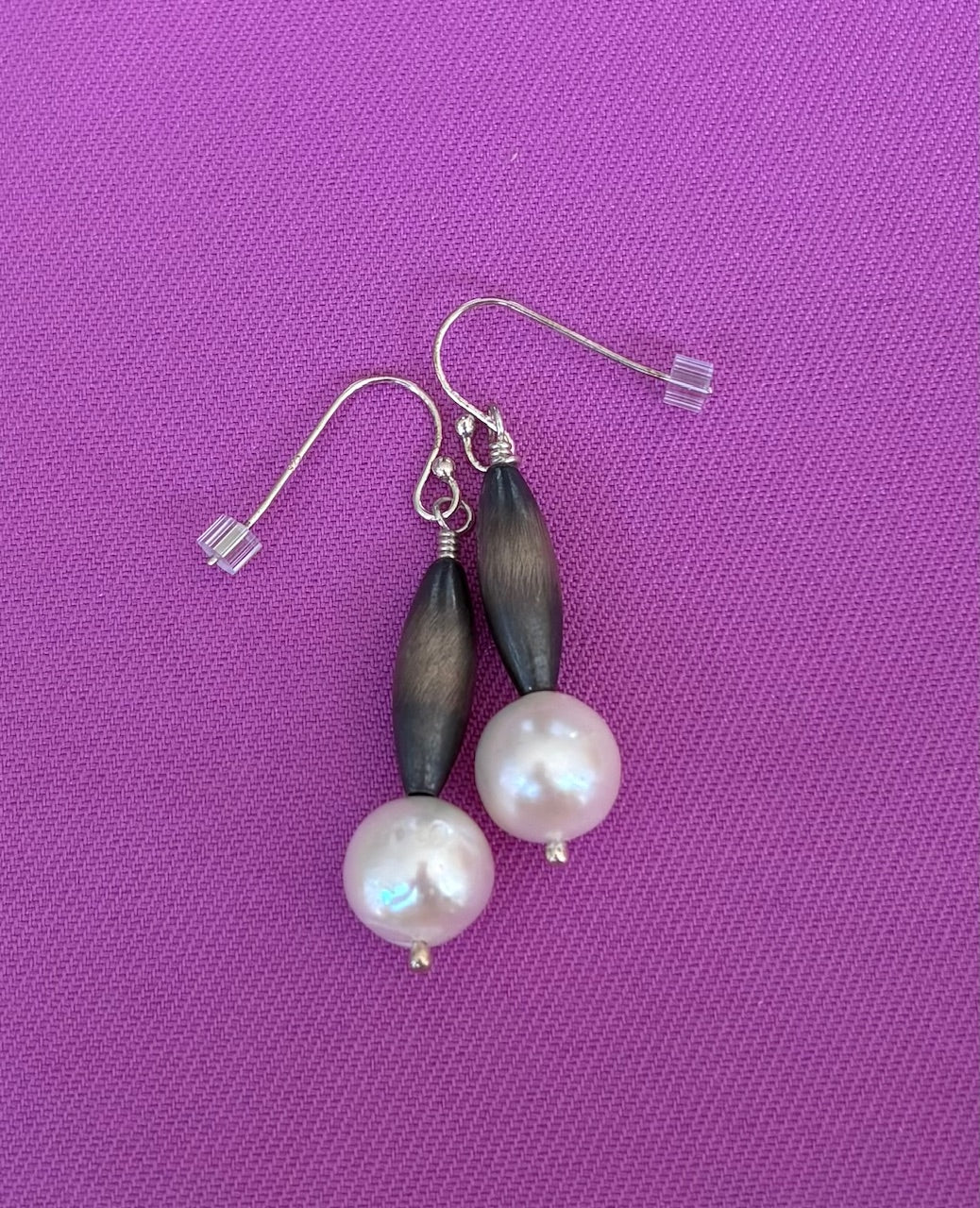 Pair of earrings with Navajo Silver and freshwater  pearls on a purple background
