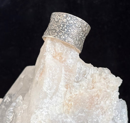 Sterling silver ring with intricate design on a crystal rock against a black background