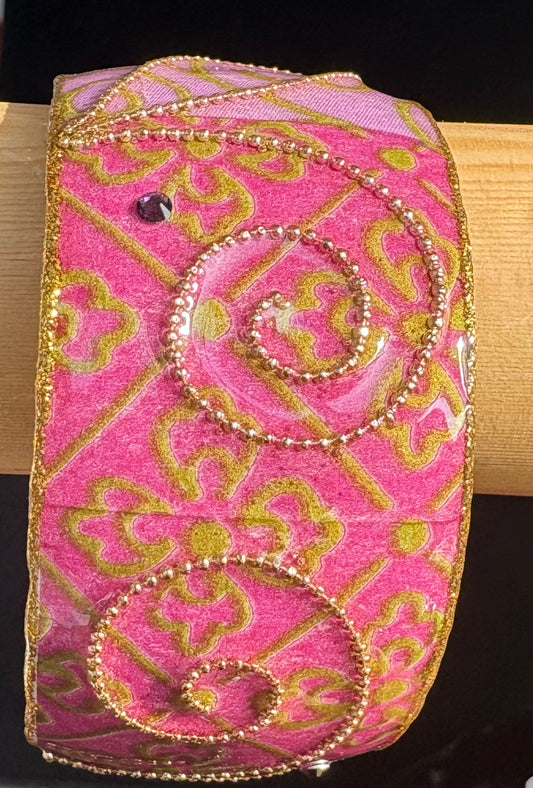 Pink paper mache and rhinestone bangle  on a wooden surface. Iris Design