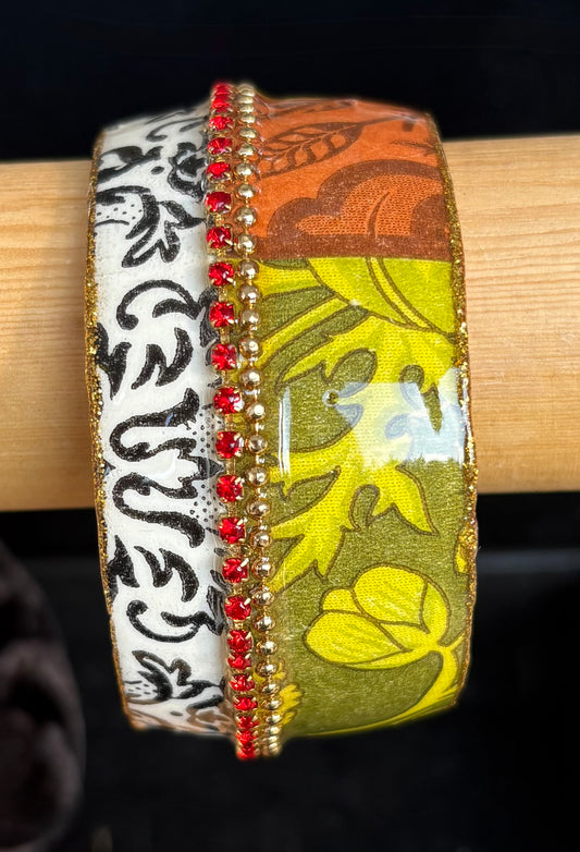 Decorative bangle with floral and abstract patterns on a display. By Iris Design