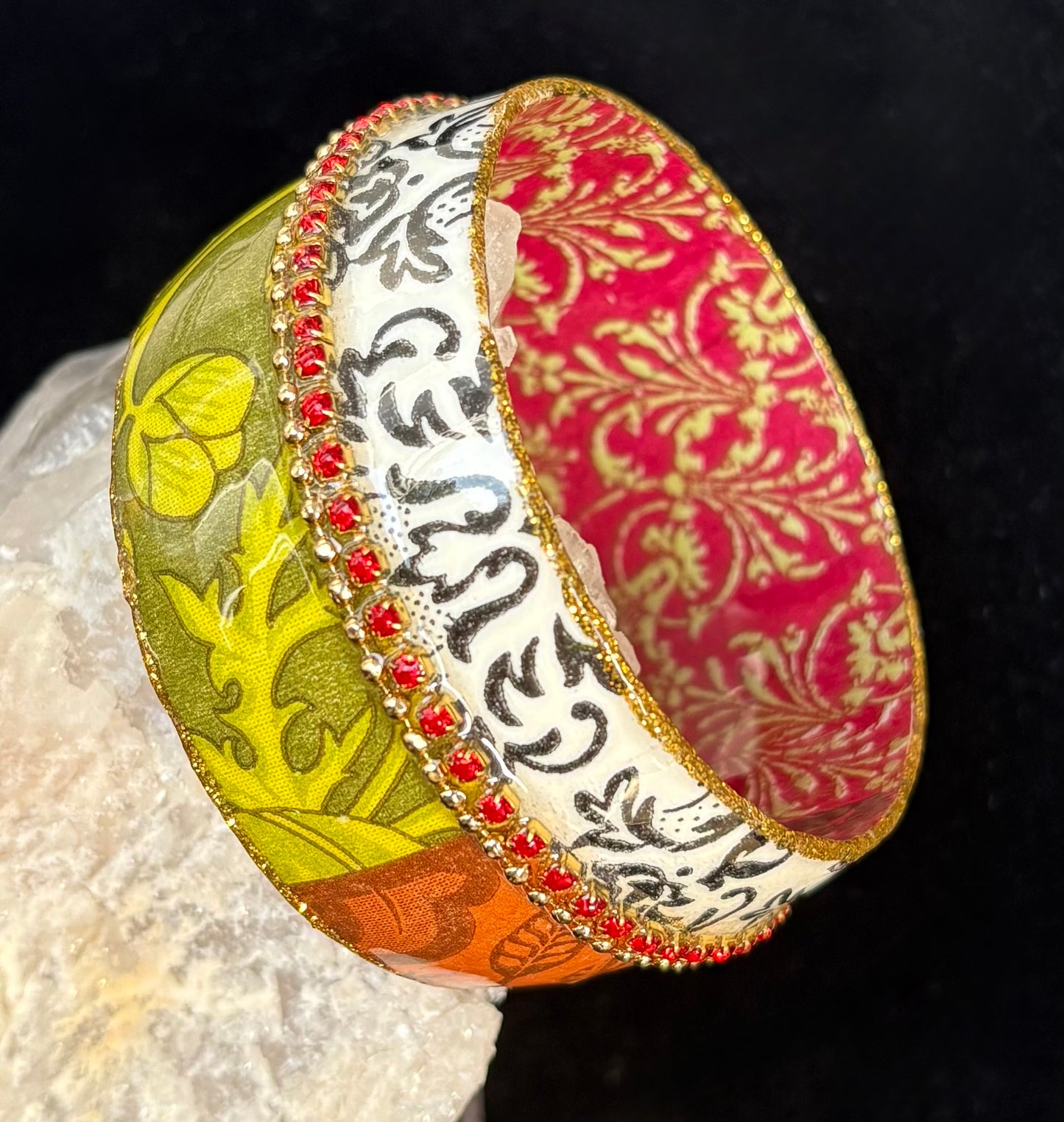 Colorful bangle with intricate patterns on a textured surface.
