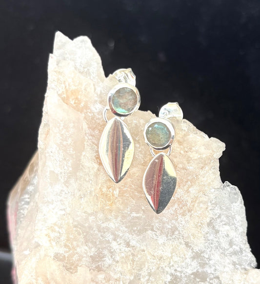 Silver earrings with gemstones on a rock background