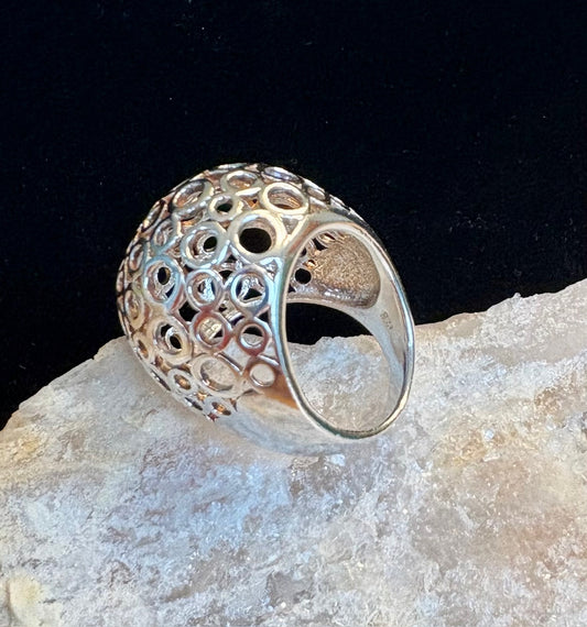 Sterling silver ring with intricate design on a rock against a black background