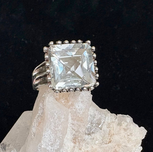 Silver ring with a large square-cut green amethyst gemstone on a black background