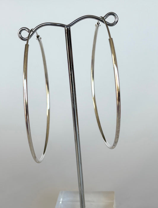 Pair of sterling silver hoop earrings on a stand against a light gray background