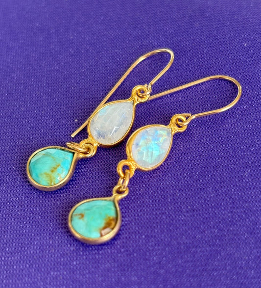 Gold earrings with turquoise and moonstone stones on a purple background