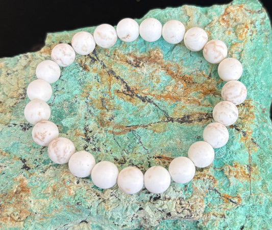 White turquoise beaded bracelet on a greenish-blue stone surface