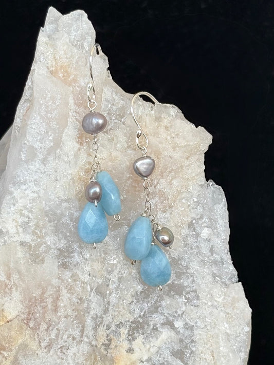Earrings with amazonite and pearl on a rock background