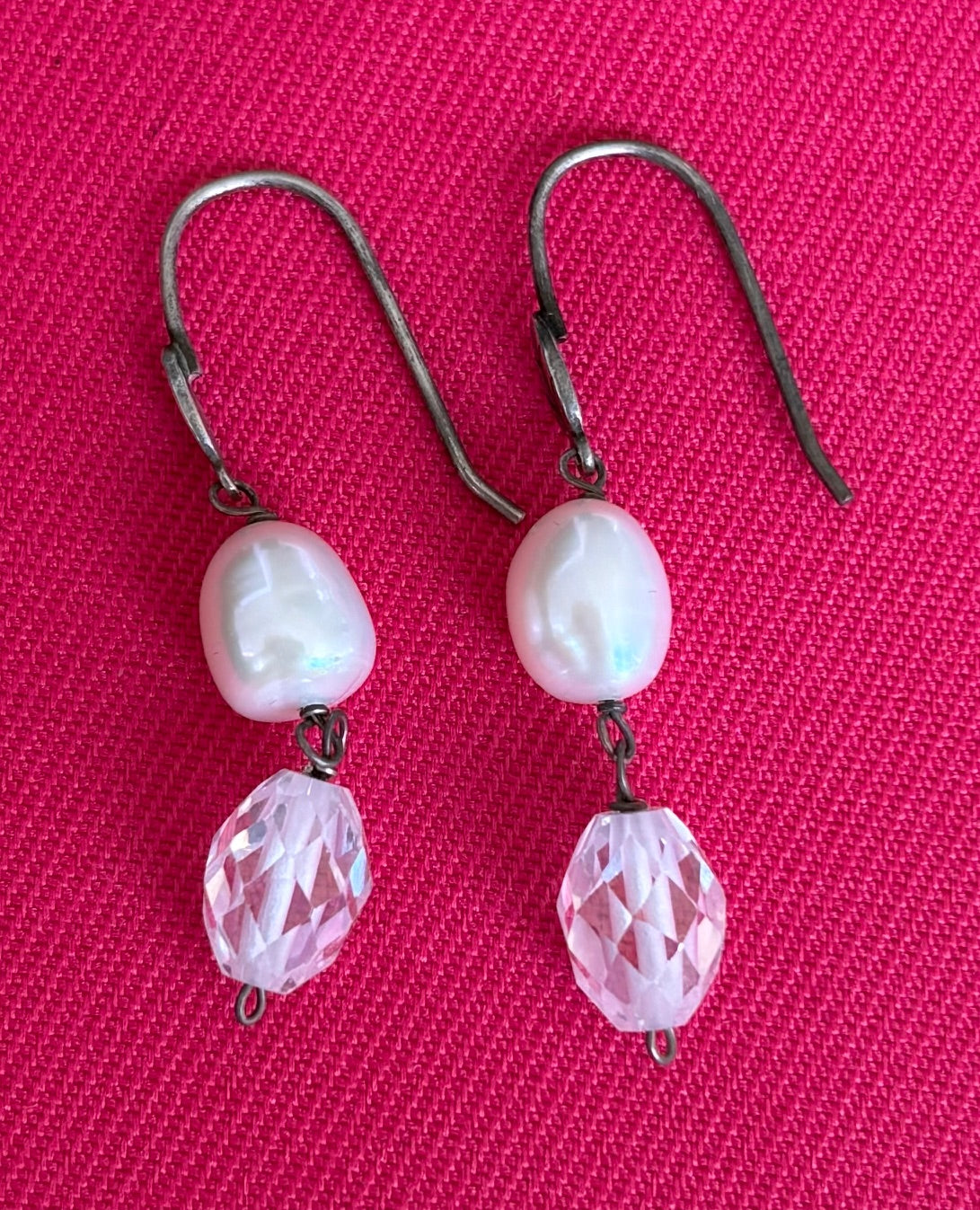 Pair of earrings with pearls and rock crystals on a pink background