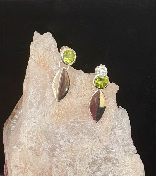 Silver earrings with green gemstones on a crystal background
