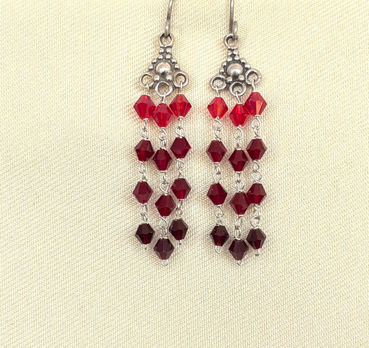 Silver earrings with red swarovski crystals on a beige background