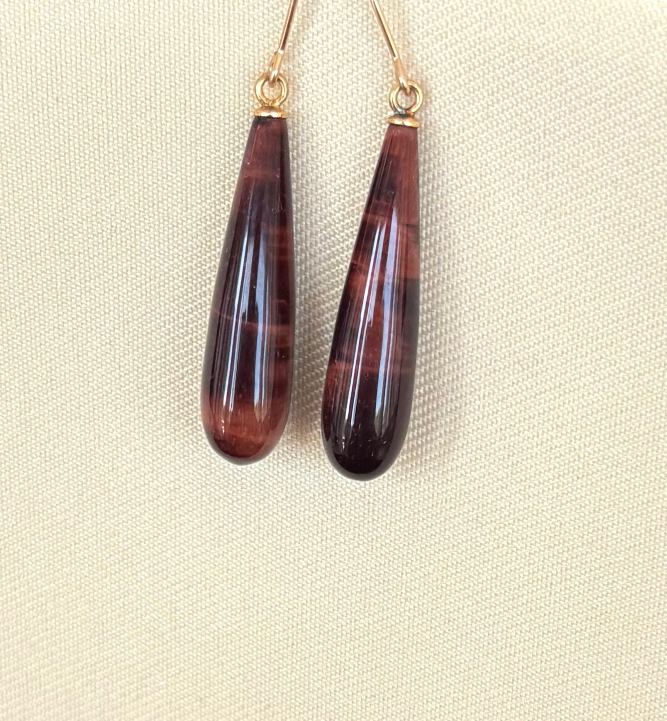Teardrop-shaped brown earrings on a beige background