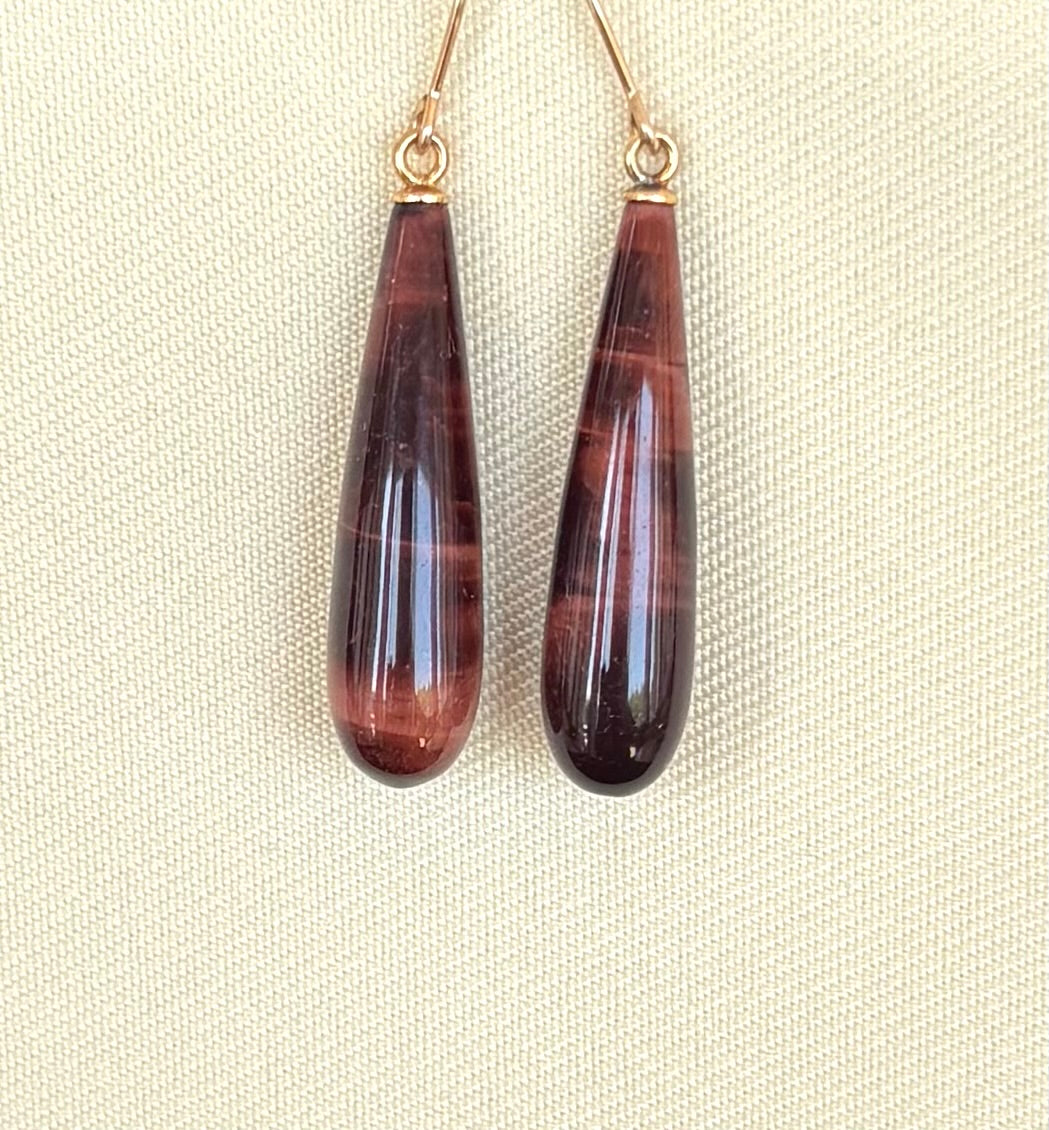 Teardrop-shaped Tiger's Eye earrings on a beige fabric background