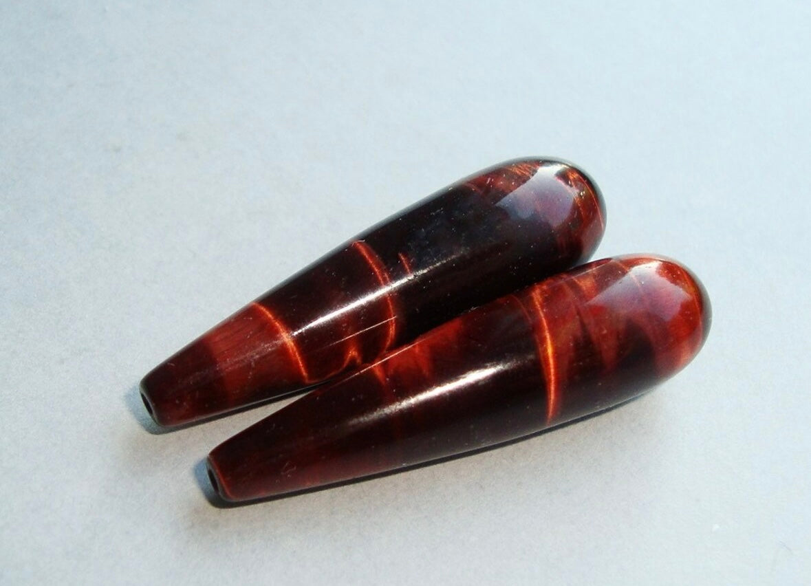 Two red Tiger's Eye stones  on a light gray background