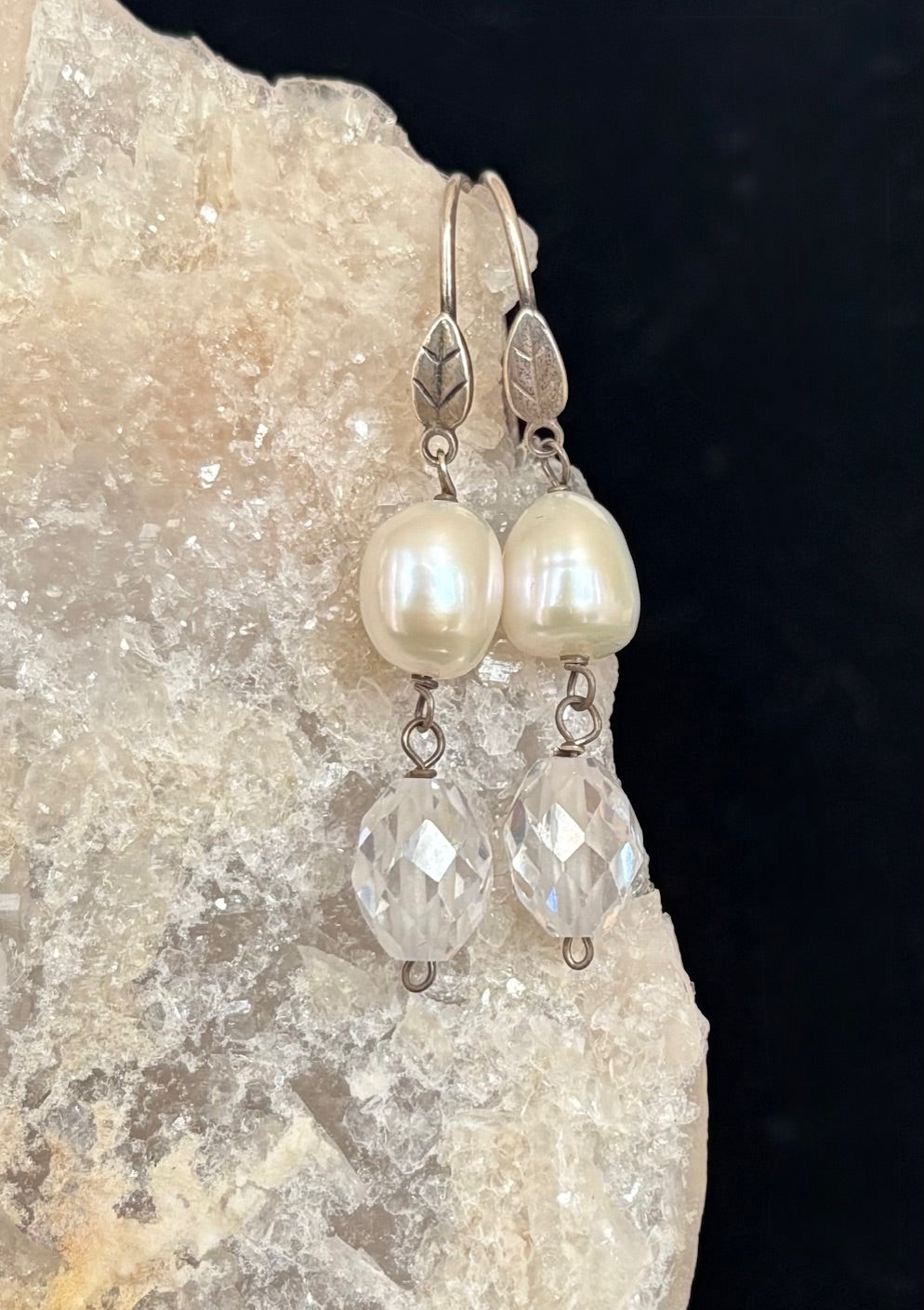 Pearl and crystal earrings on a stone background