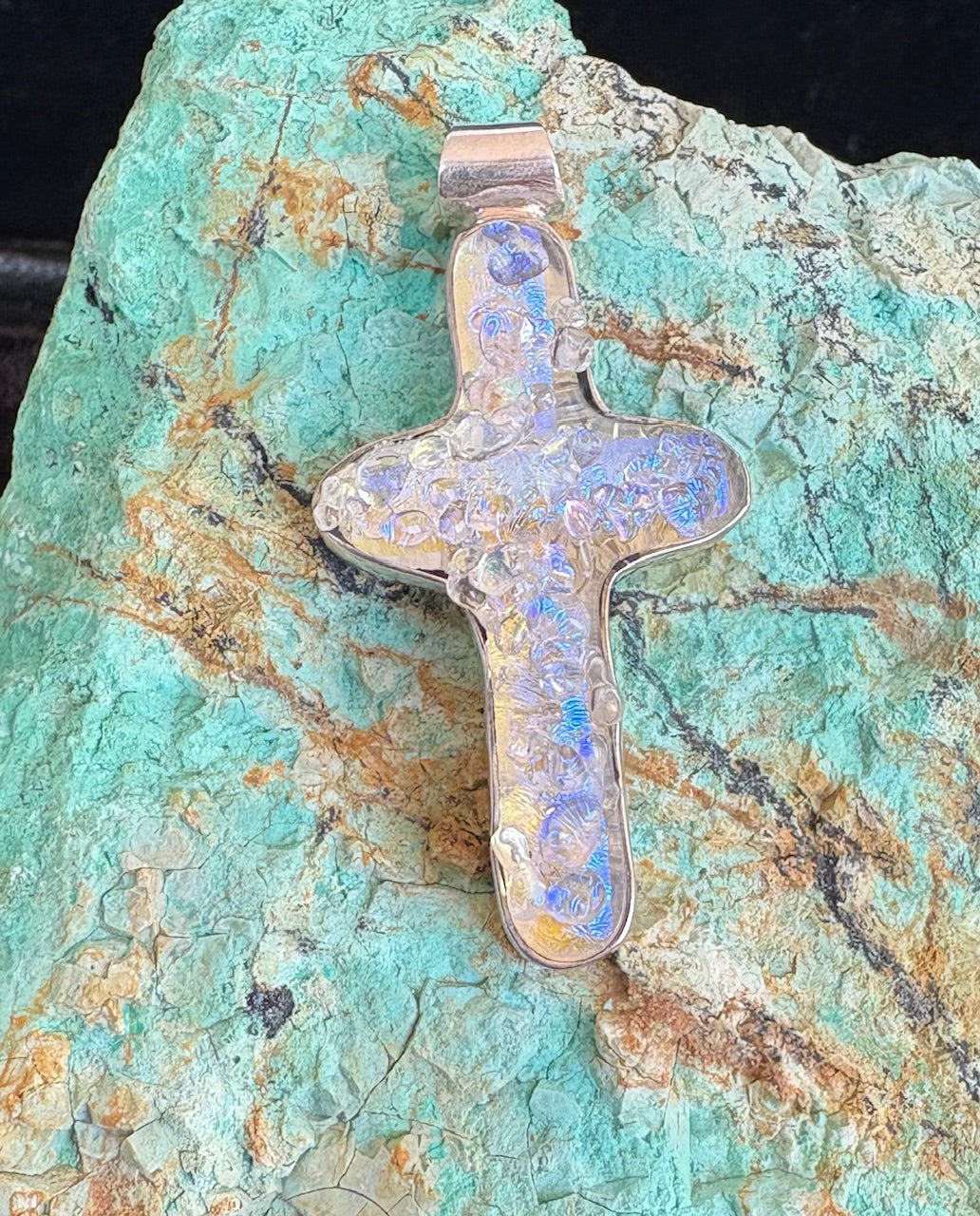 Cross-shaped pendant on a turquoise stone background